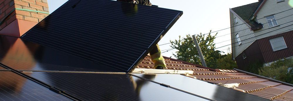 Person installiert Solarpanel auf Dach